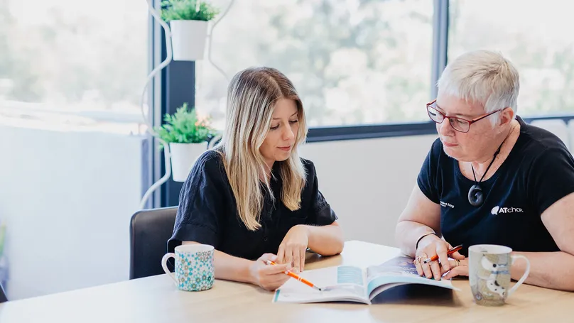 Two women studying a booklet together.