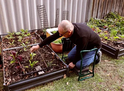 older man kneeling-chair-garden