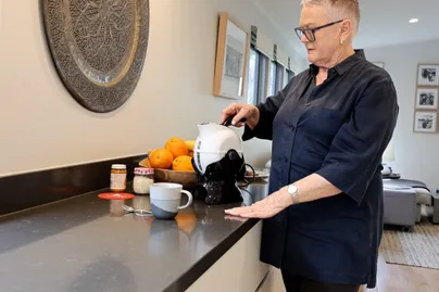 Older woman using a kettle.