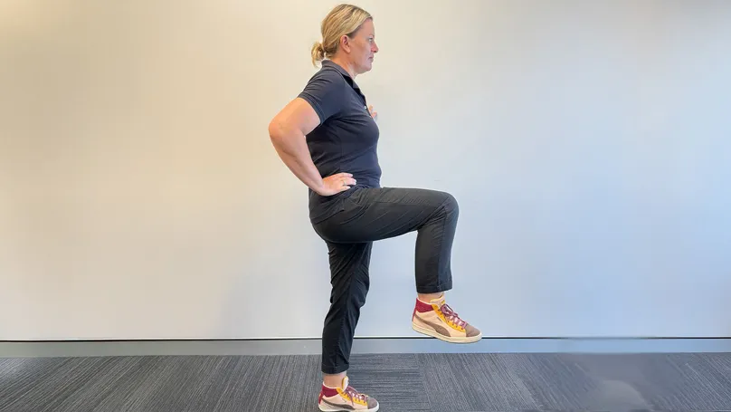 A woman doing a one leg stand.