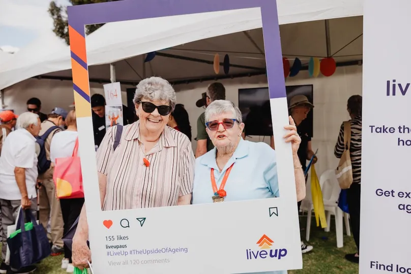 Two ladies holding a social media card for Liveup